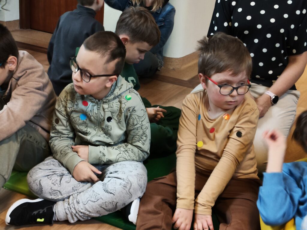 uczniowie z widocznymi na ubraniach kolorowymi kropkami